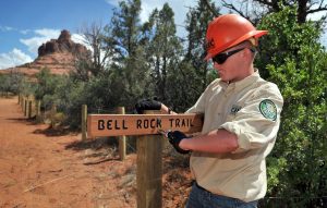 Sedona Red Rock High School sophomore Brent Buntin, 15, tightens the Bell Rock Trail sign near the new trailhead Wednesday, July 14, near the Village of Oak Creek on the Coconino National Forest. The nine-person Youth Conservation Corps team worked three weeks on the new trail removing brush, building fences and erecting signs for the trail, which now leads more directly to Bell Rock.